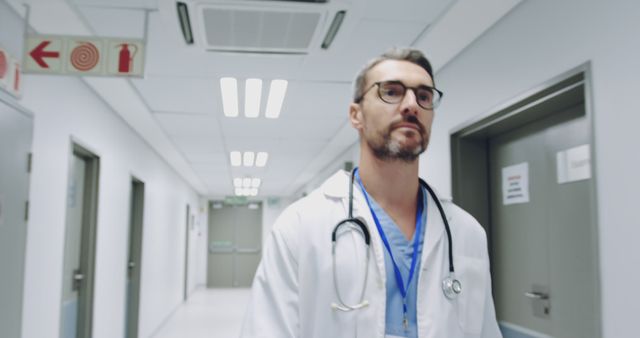 Caucasian doctor walking in a hospital corridor. He's in a professional setting, symbolizing healthcare and medical expertise.