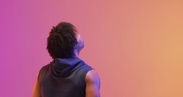 Young man with afro hair looking up against vibrant background - Download Free Stock Images Pikwizard.com