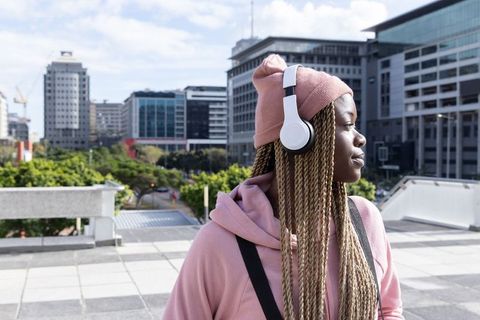 African american woman wearing headphones on urban rooftop terrace with city skyline