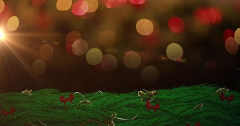 Festive fir garland with red bows and twinkling bokeh lights