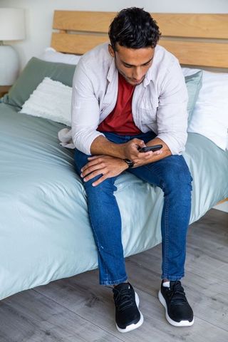 Man Relaxing on Bed Using Smartphone in Contemporary Home