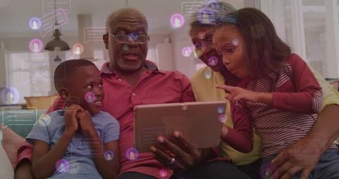 Multigenerational family sharing tablet on couch, grandparents and grandchildren bonding