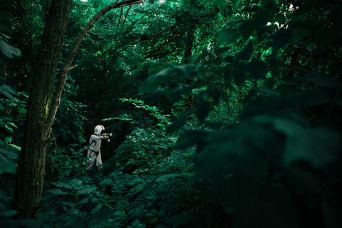 Explorer in space suit venturing through dense jungle