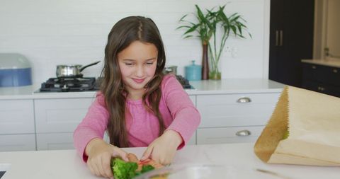 Joyful Girl Unpacking Groceries in Modern Kitchen