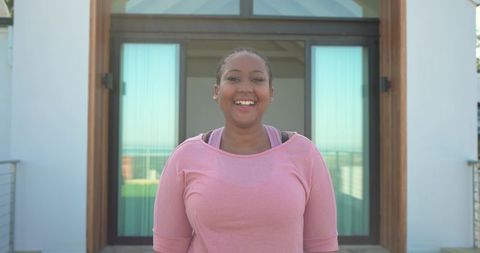 Smiling mid-adult african american woman on modern balcony wearing pink activewear