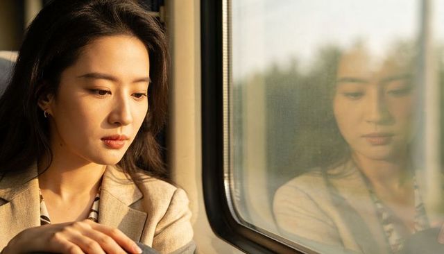 Sunlit commuter gazing through train window, reflective portrait, contemplative travel moment