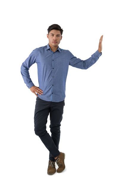 Portrait of young businessman standing with hand on hip against white background