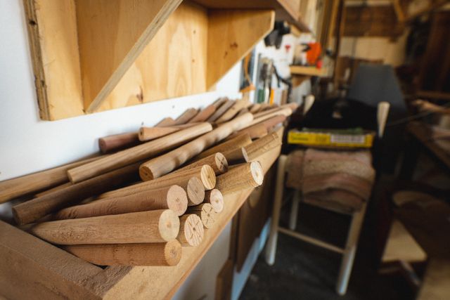 Wooden dowels neatly arranged on a shelf in a carpentry workshop. Ideal for illustrating concepts related to woodworking, craftsmanship, and DIY projects. Useful for blogs, articles, and advertisements focused on carpentry, handmade crafts, and wood manufacturing.