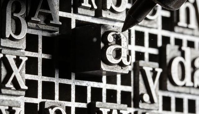 Closeup letterpress metal type tray featuring lowercase 'a' with type pick
