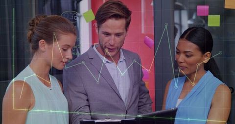 Business team collaborating over tablet with analytics charts overlaying glass wall, sticky notes