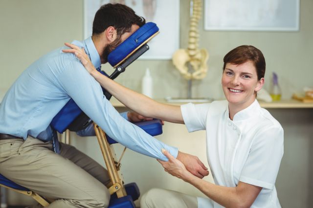 Physiotherapist giving arm massage to male patient in clinic. Ideal for use in healthcare, wellness, and medical treatment contexts. Useful for illustrating physical therapy, rehabilitation, and professional healthcare services.