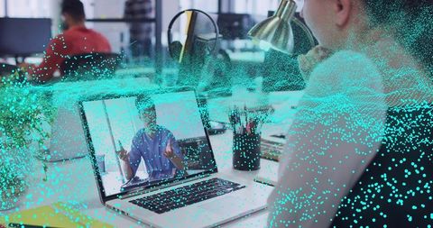 Korean man joining video call at desk with turquoise data overlay for remote teamwork