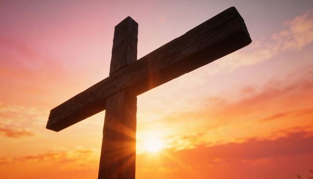 Aged wooden cross standing at horizon during glowing sunset with sun rays and dramatic sky