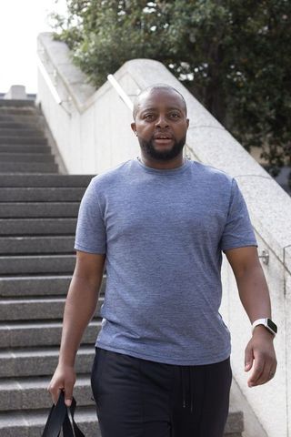 African american man walking down plaza stairs carrying tote bag, casual urban lifestyle