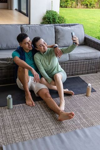 Asian couple taking selfie on patio after outdoor yoga, relaxing active lifestyle