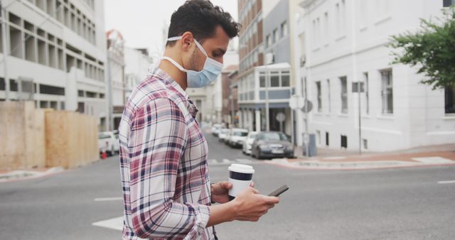 Man Wearing Mask Holding Coffee and Phone Outdoors - Download Free Stock Images Pikwizard.com