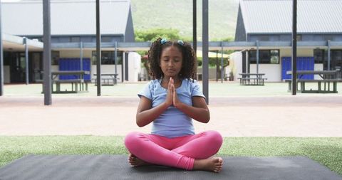 Mindful child in yoga pose outdoors at school