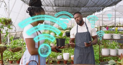Nursery staff demonstrating smartphone ar wifi connectivity for customer in greenhouse