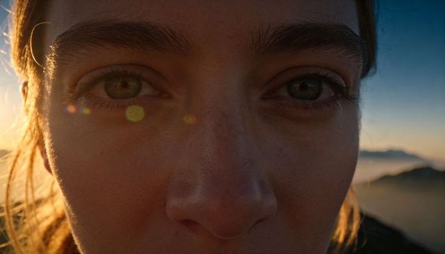 Closeup woman face filling frame capturing golden hour backlight on mountain ridge