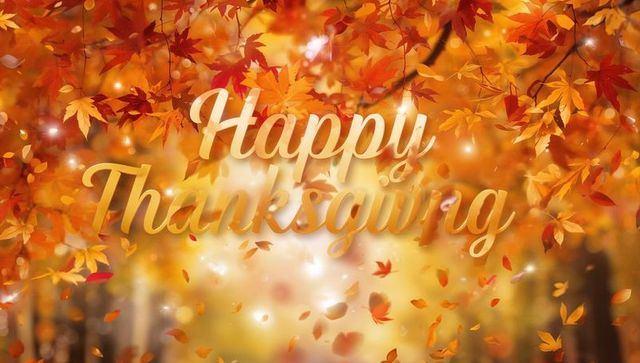 Golden happy thanksgiving script over falling autumn leaves and warm sunlit bokeh