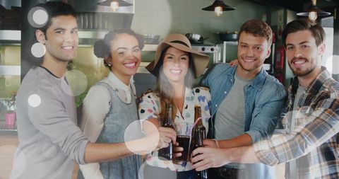 Young friends celebrating with drinks at bar counter toasting with bottles and glass