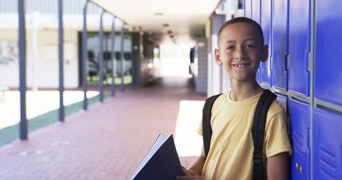 Smiling Boy with Backpack by Lockers in School Corridor
