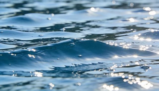 Sparkling turquoise ocean surface with gentle ripples and sun glints, bokeh glow