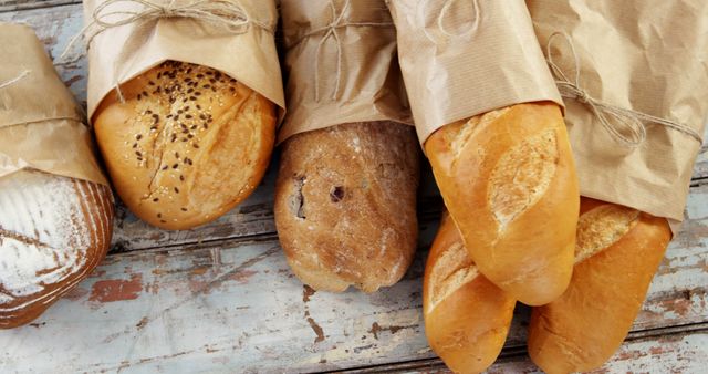 Assorted Freshly Baked Breads Wrapped in Paper on Rustic Wooden Table - Download Free Stock Images Pikwizard.com