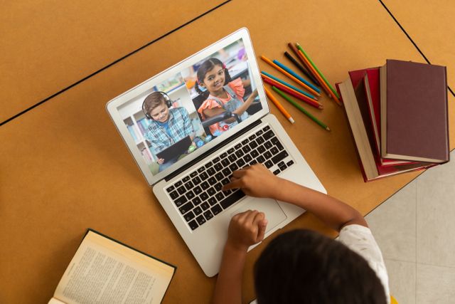 Perfect for illustrating online education, home schooling, and virtual learning environments. This visual captures a young student interacting with a laptop watching a virtual classroom session featuring other children. Ideal for web design, educational blogs, articles on distance learning, and e-learning platforms.