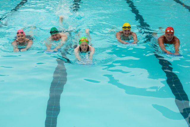 Group of swimmers using kickboards in a pool, perfect for illustrating teamwork, aquatic sports, and fitness training. Ideal for use in health and fitness articles, swimming tutorials, and promotional materials for swimming classes or aquatic centers.