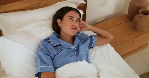 Woman Rests in Bed with Blue Pajamas Embracing Peaceful Atmosphere