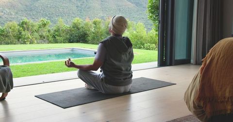 Senior Man Practicing Meditation Overlooking Tranquil Pool