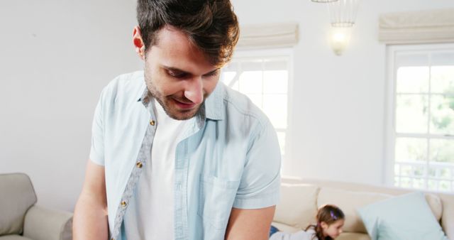 Father is bonding with his young daughter in living room, emphasizing creation of happy family moments. Ideal for use in parenting blogs, family lifestyle magazines, advertisements promoting family-oriented products, or articles on positive parenting and home life.