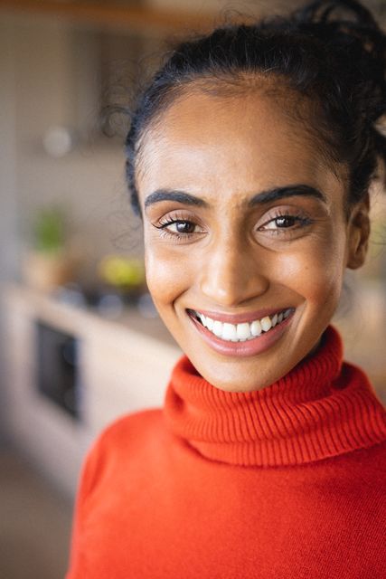 Close-up portrait of biracial mid adult woman wearing orange turtleneck t-shirt at home. Unaltered, lifestyle, happy and home concept.