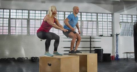Couple performing plyometric box jumps in industrial gym boosting strength and balance