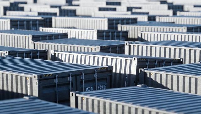 Organized rows of shipping containers in port yard with corner castings and locking bars