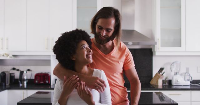Portrait of biracial couple smiling and hugging in the kitchen at home. staying at home in self isolation in quarantine lockdown