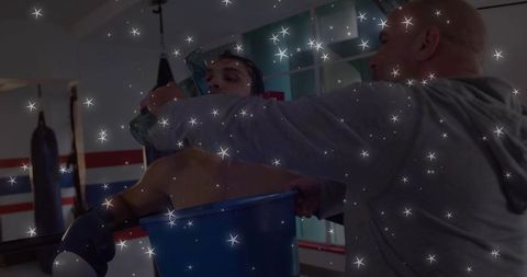 Boxer recovering in blue ice tub with trainer applying ice pack after intense ring workout