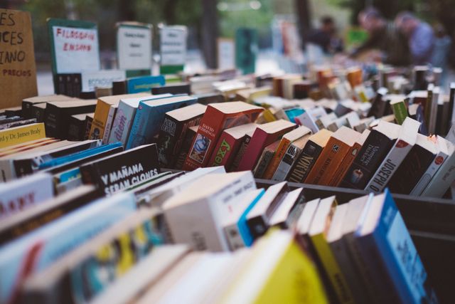 Street market book stall filled with a variety of books displayed outdoors. Ideal for illustrating street markets, book collections, reading culture, and outdoor commerce. Suitable for advertising book fairs, promoting literary events, or depicting vibrant marketplace scenes.