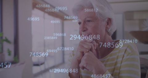 Contemplative senior woman engaging with virtual data at home