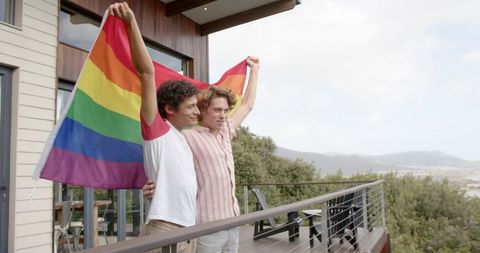Diverse couple celebrating lgbtq pride on scenic balcony