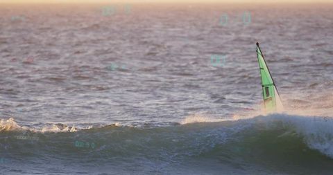 Windsurfer battling breaking wave at sunrise with green sail, ocean spray and horizon