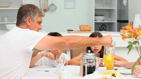 Happy Family Having Breakfast with Orange Juice and Cereals