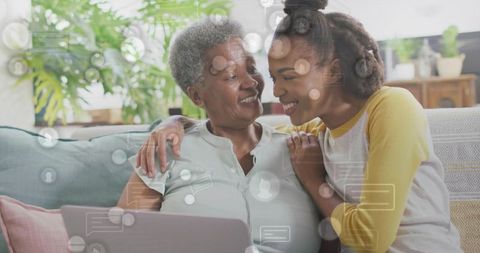 Multigenerational bonding: grandmother and granddaughter sharing laptop, laughing together