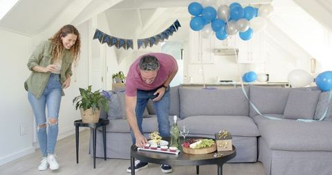Couple Preparing Living Room for Birthday Celebration with Balloons