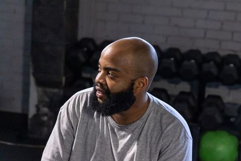 African american man resting on bench in gym with dumbbells and kettlebell