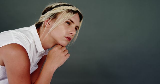 A young Caucasian woman with a braided hairstyle appears contemplative, with copy space. Her gaze is directed off-camera, suggesting a moment of introspection or decision-making.
