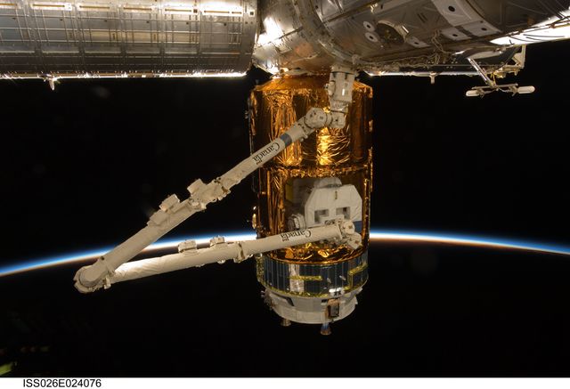 Features Japanese H-II Transfer Vehicle docked to the Harmony node on ISS, held by Canadaarm2 with Earth's atmosphere and space as a backdrop. Useful for content on space exploration, international collaboration, astronaut missions, and satellite technology.