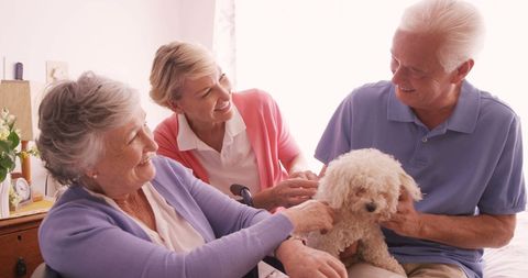 Senior couple and adult child bonding with poodle at home