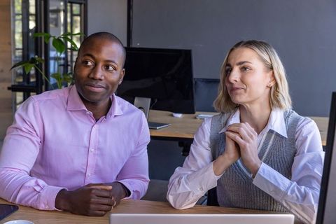 Diverse Coworkers Engaged in Professional Discussion at Office Desk